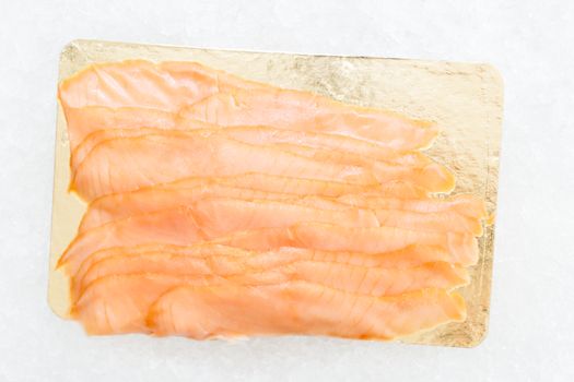 Close-up of sliced smoked salmon on a golden platter, perfect for gourmet seafood dishes.
