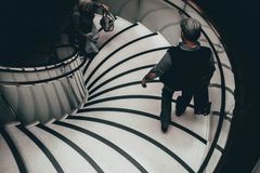 A high-angle view of people descending an elegant spiral staircase in London.