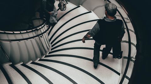 A high-angle view of people descending an elegant spiral staircase in London.