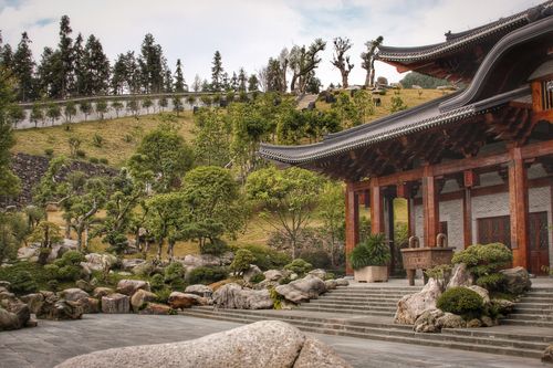 Free Tranquil view of a traditional Chinese temple surrounded by lush garden and rocks. Stock Photo