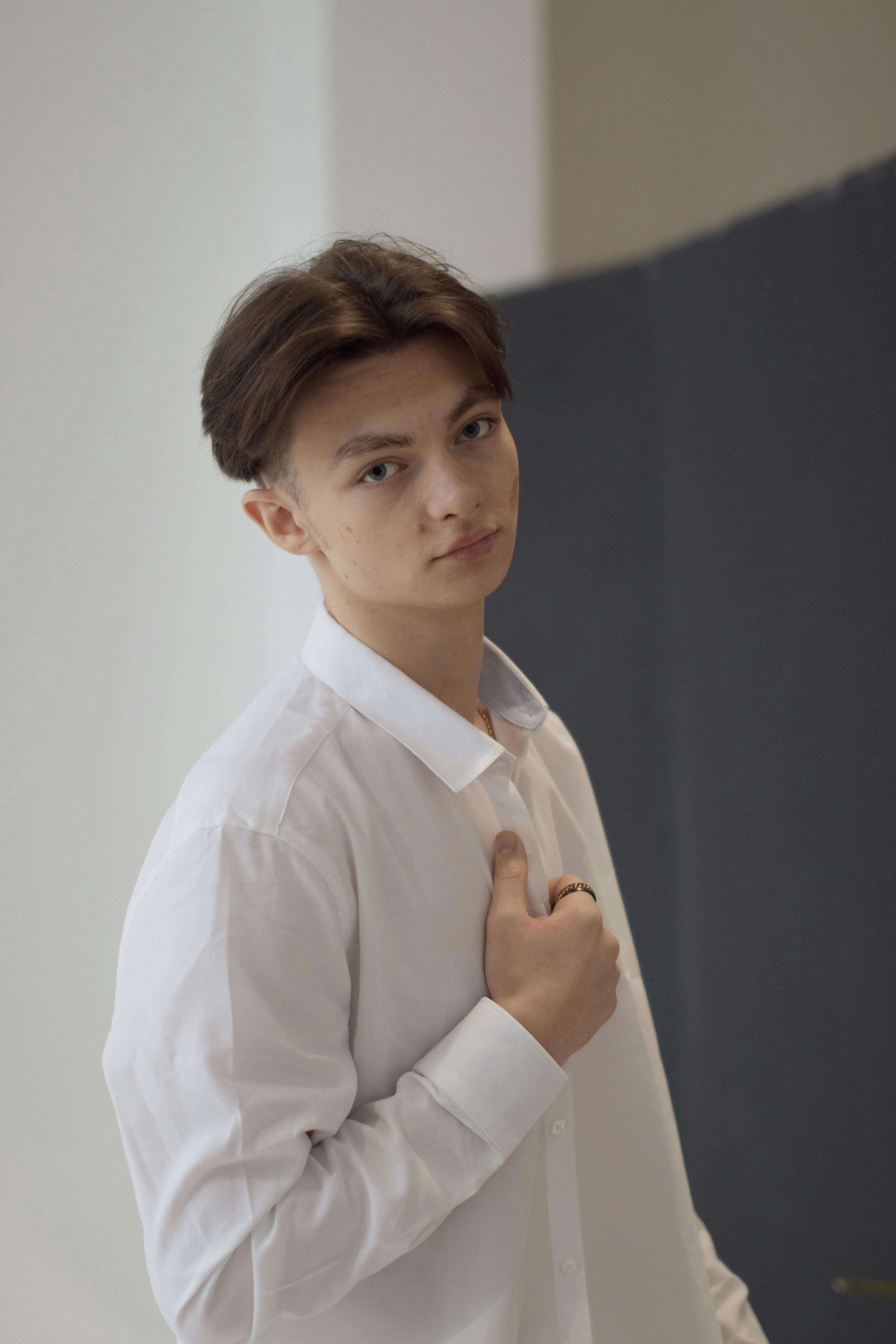 Portrait of a young man in a white shirt standing indoors, looking at camera.