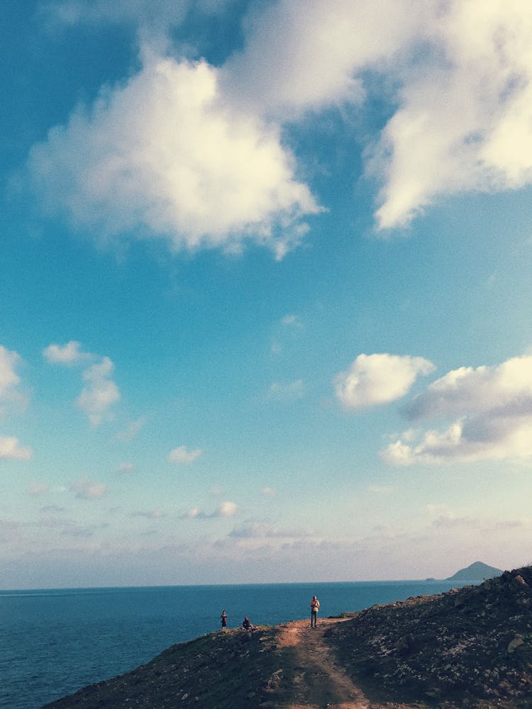 People Walking On Hill Near Water