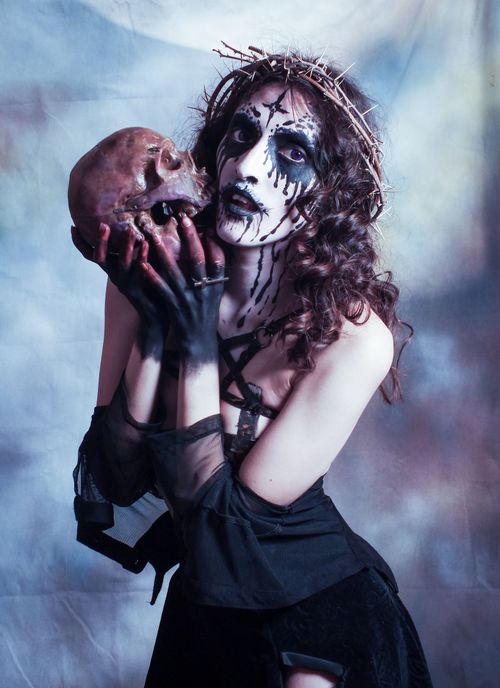Free Eerie portrait of a woman in a spooky costume holding a skull, perfect for Halloween themes. Stock Photo