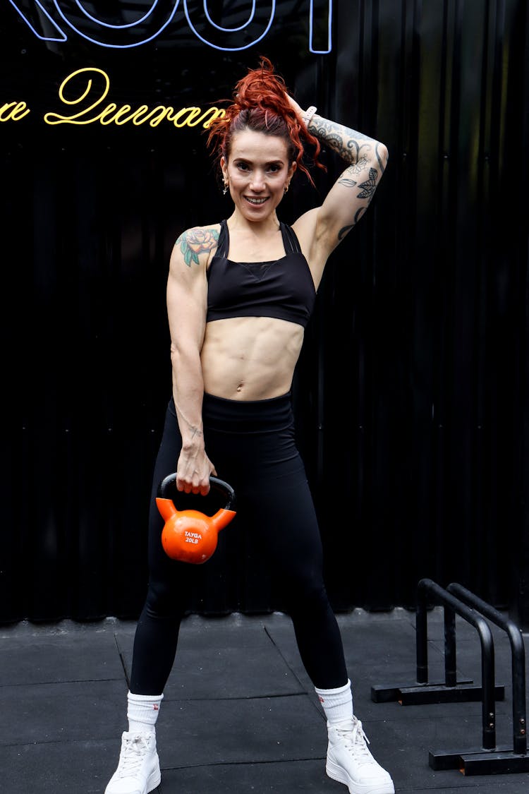 A Tattooed Woman Holding A Kettlebell