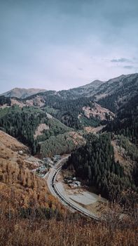 Stunning aerial view of the Almaty mountainous landscape, highlighting autumn colors and winding roads.