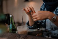 一只涂着五颜六色指甲的手在室内的桌上端着饮料