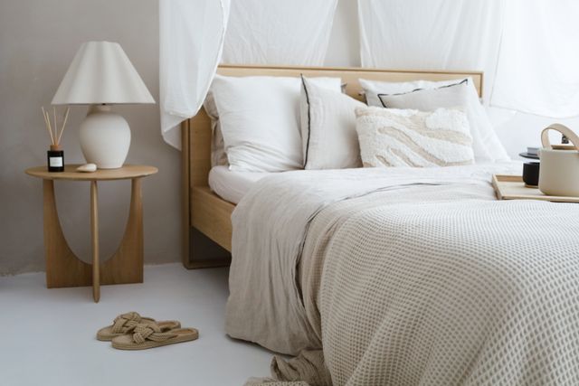 A neutral bedroom with waffle-weave bedding, linen throw and a pale bedside lamp — photo by Natalia Walusiak on Pexels