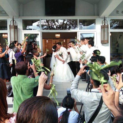 Фотография целующейся супружеской пары в окружении свадебной вечеринки.
