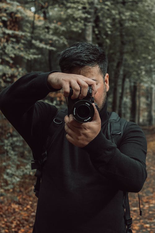 A Man in a Black Sweater Using a Camera