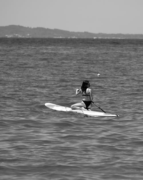 Black and White Photo of Woman Paddle Boarding