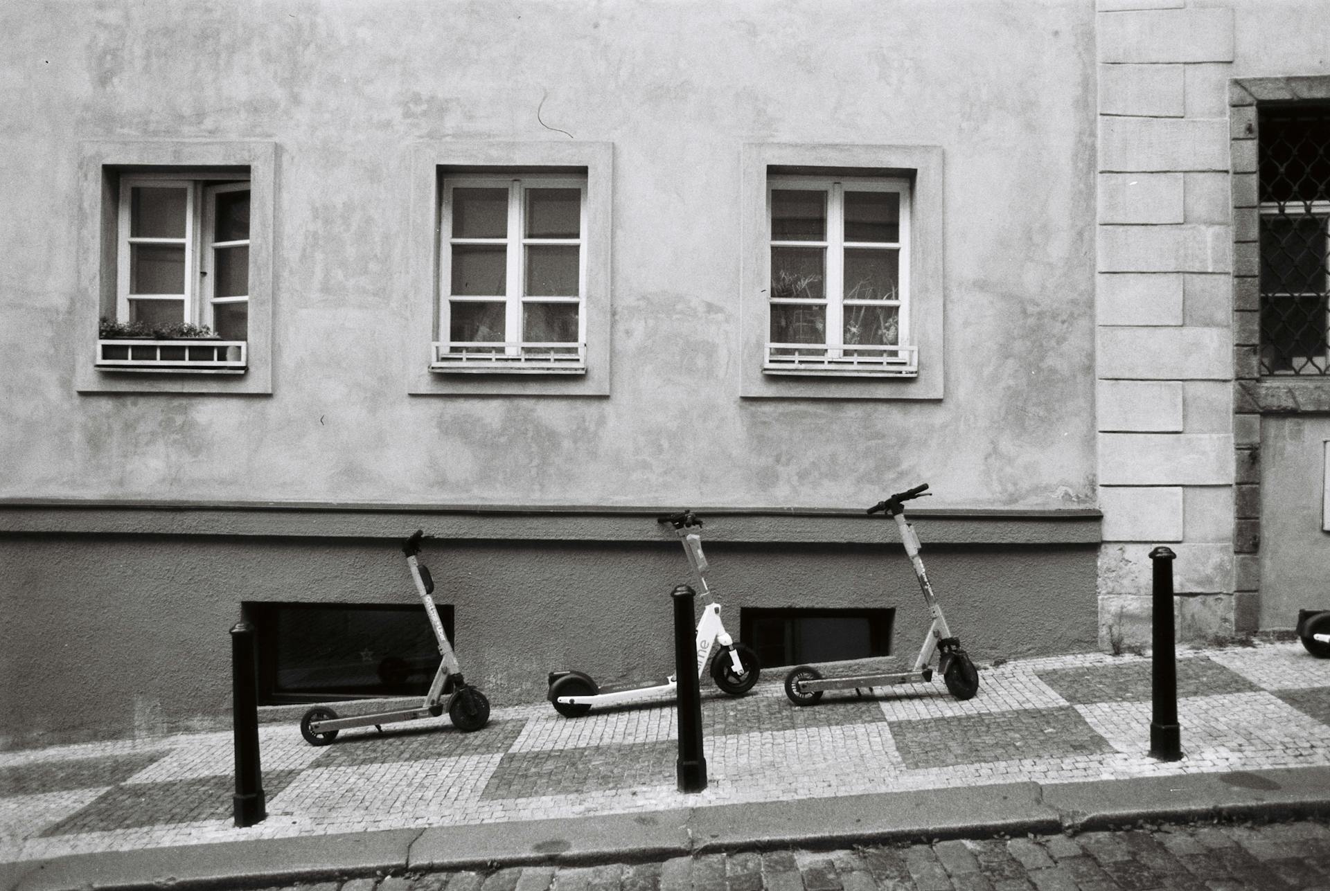 A grayscale photograph featuring scooters parked by a historic building in Prague.
