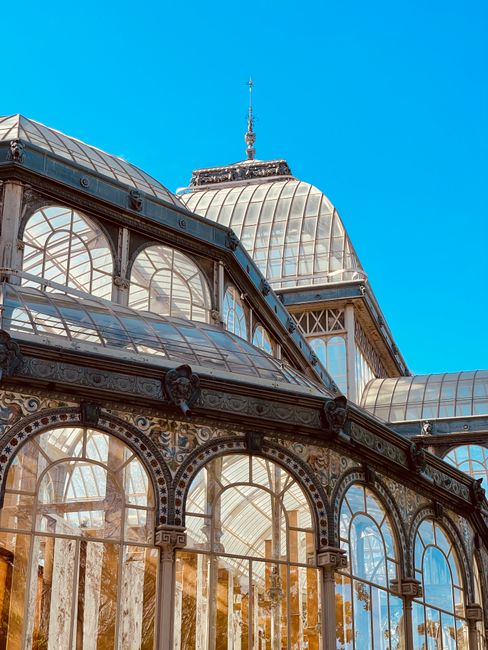Detailed view of the Palacio de Cristal's architecture in Retiro Park, Madrid, under a clear blue sky.