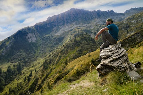 Man in Blue Shirt Sitting on Rock 