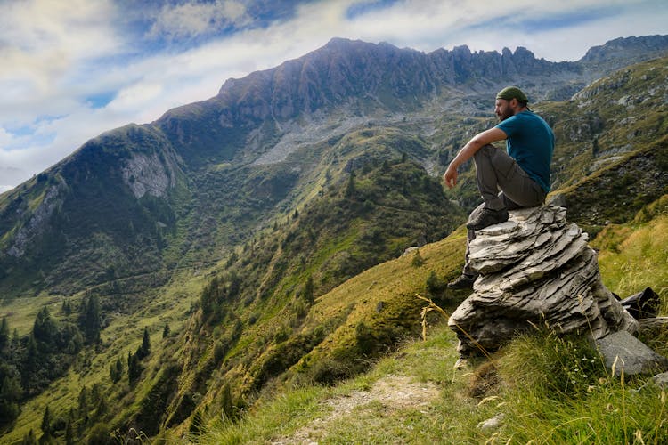 Man In Blue Shirt Sitting On Rock 