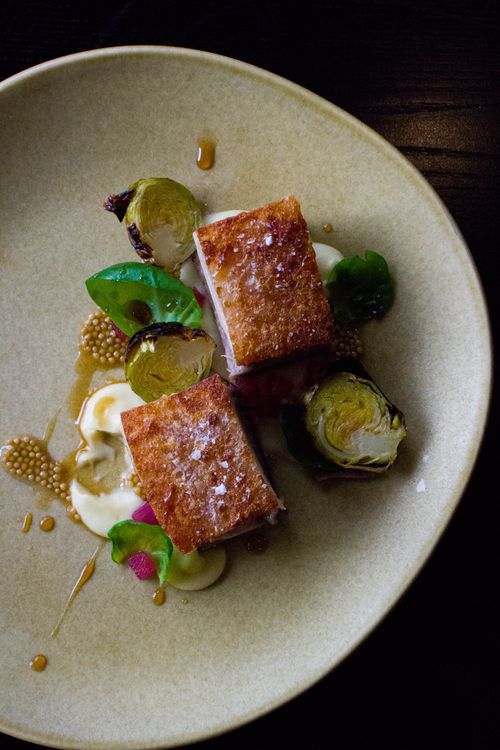 Free Delicious crispy pork belly served with a gourmet presentation of Brussels sprouts and mustard seeds. Stock Photo