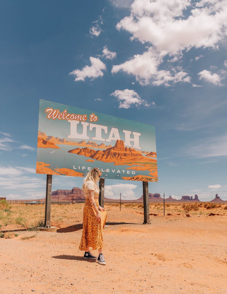 Woman Posing Near Welcome To Utah Advertisement