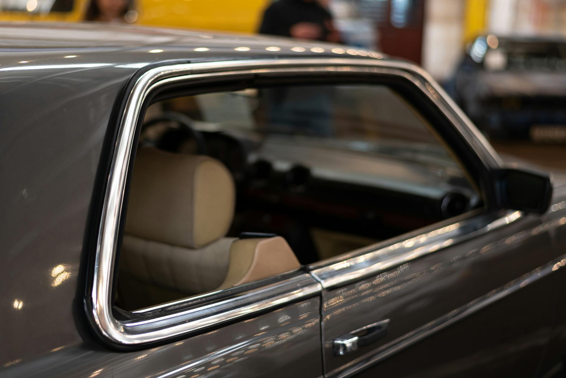 Detailed view of a classic car's chrome window trim and interior seen indoors.