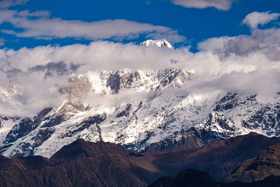Stunning view of snow-covered Himalaya mountain peaks under a vivid blue sky with clouds.