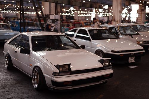 Free Classic white cars displayed in an indoor automotive showroom with festive lighting. Stock Photo