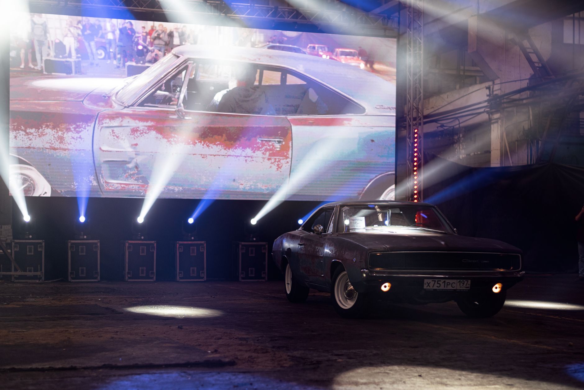 Classic muscle car illuminated by stage lights in a nostalgic indoor venue.