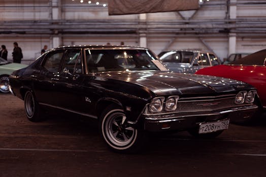Classic black vintage car showcased at an indoor auto exhibition, highlighting retro design.