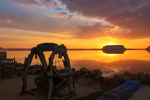 A Person Sitting on a Wooden Swing while Looking at the Beautiful Sunset