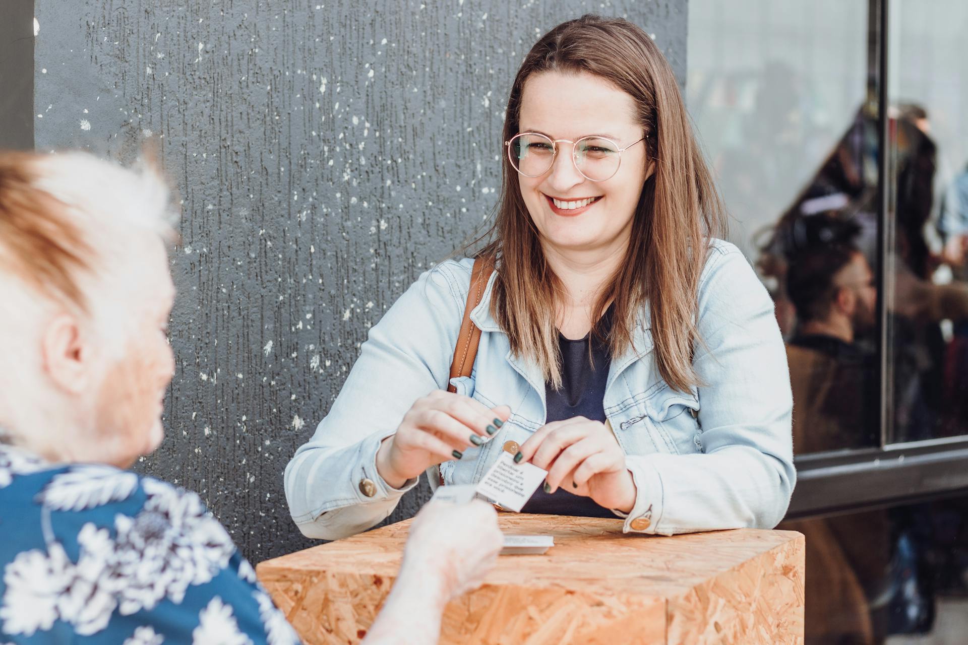 A cheerful woman in a denim jacket shares a joyful moment at a street market in Sorocaba, Brazil.