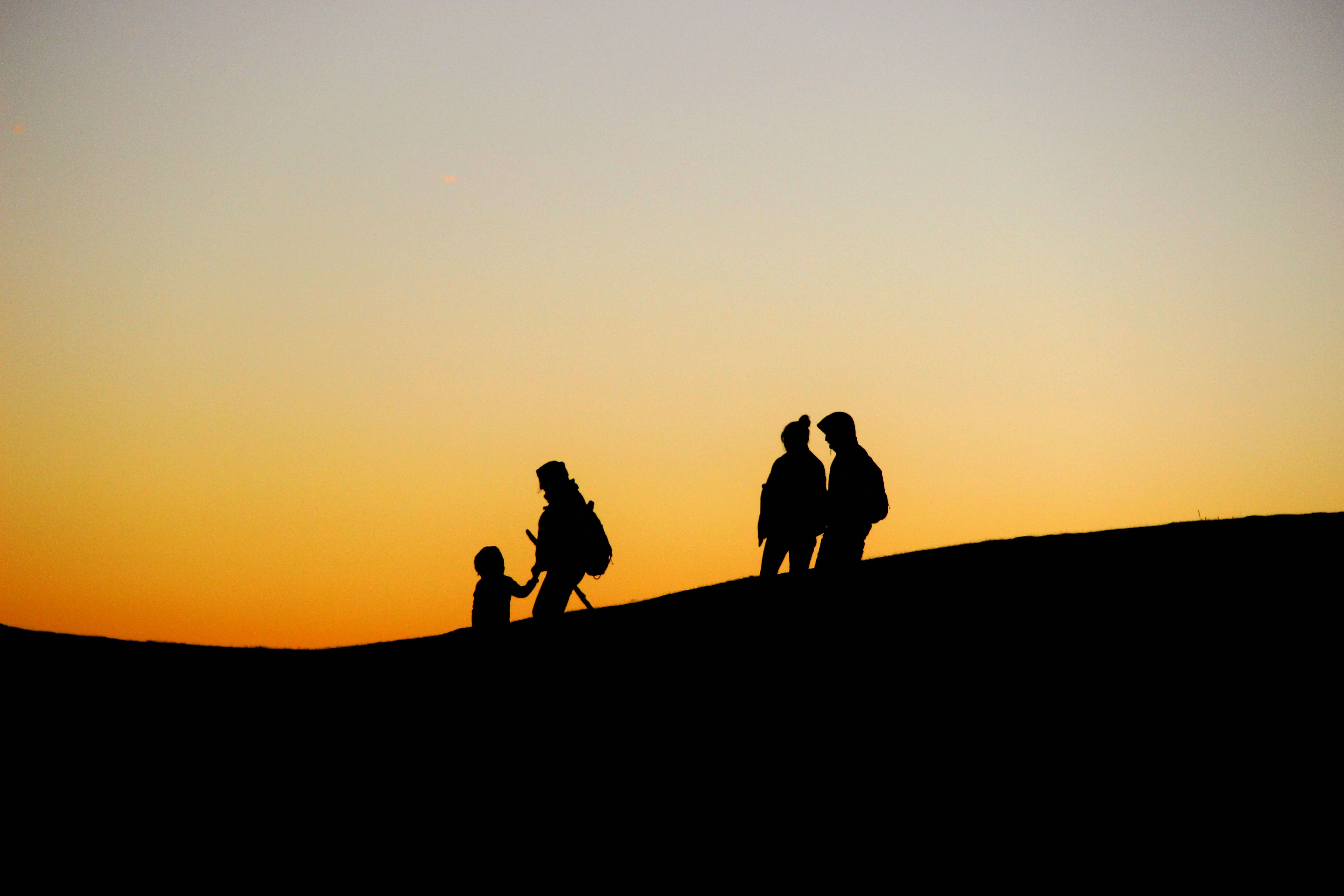 Silhouetted hikers against a colorful sunset sky, conveying adventure and serenity.