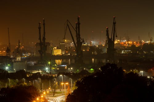 Construction Cranes over Buildings in City at Night
