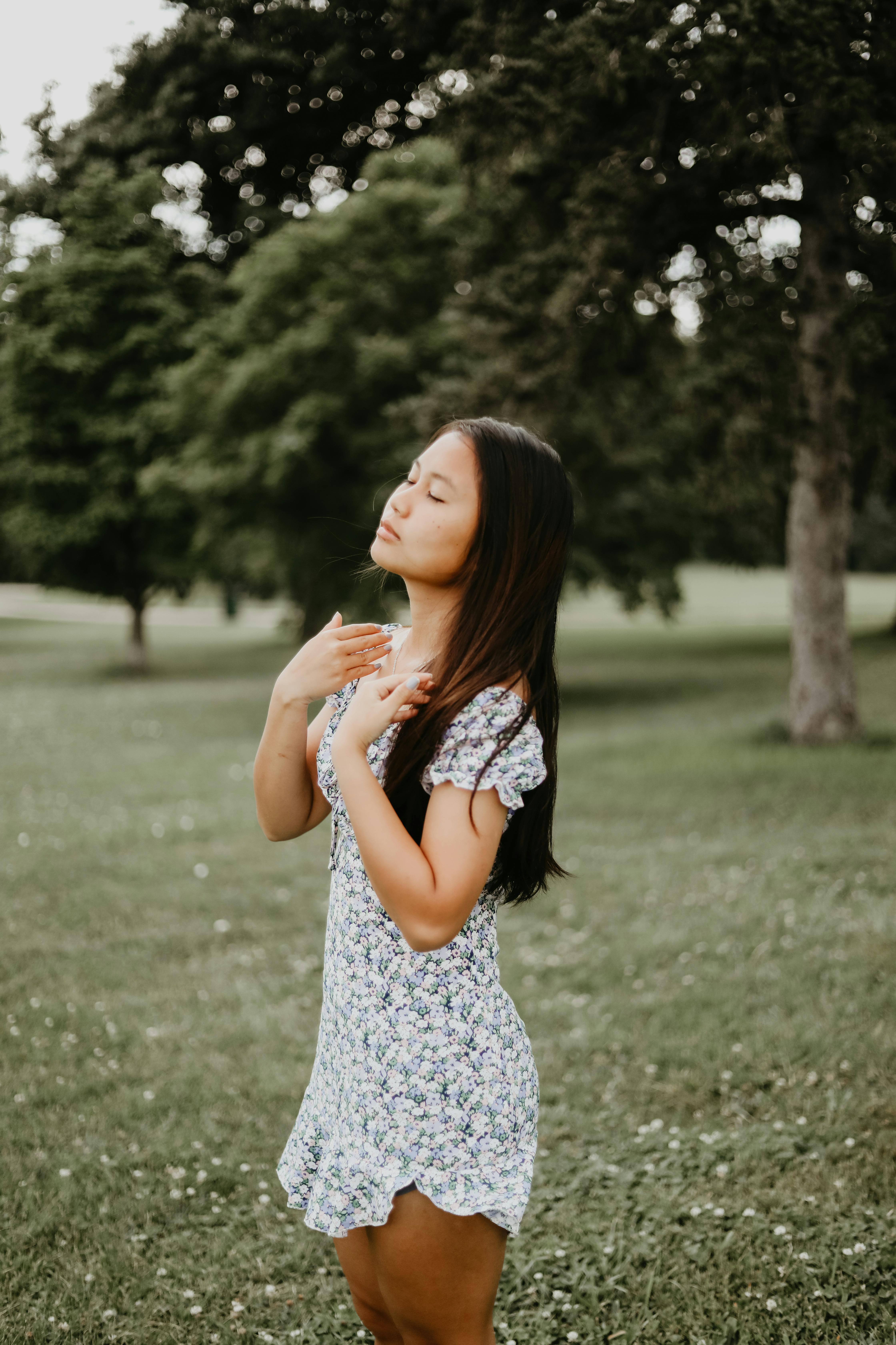 a woman in floral dress standing on grass field