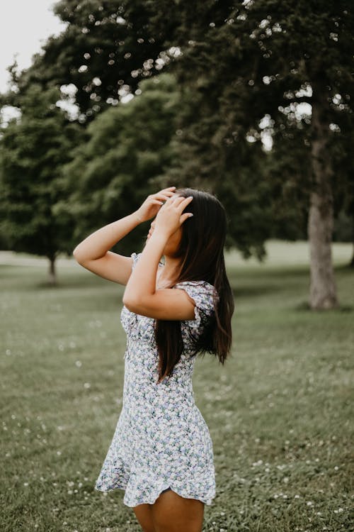 A Woman in White and Blue Dress Holding Her Hair