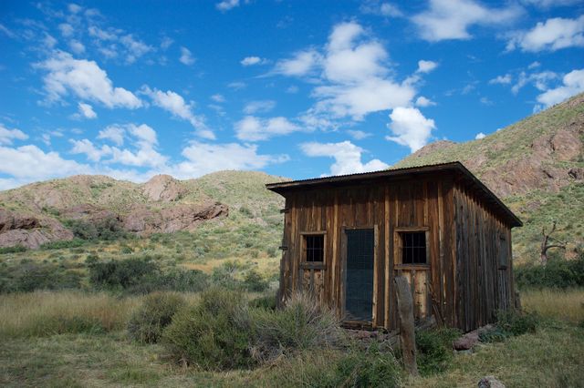 Weathered timber cabin in high desert scrub under a bright sky — photo by Jonathan West on Pexels