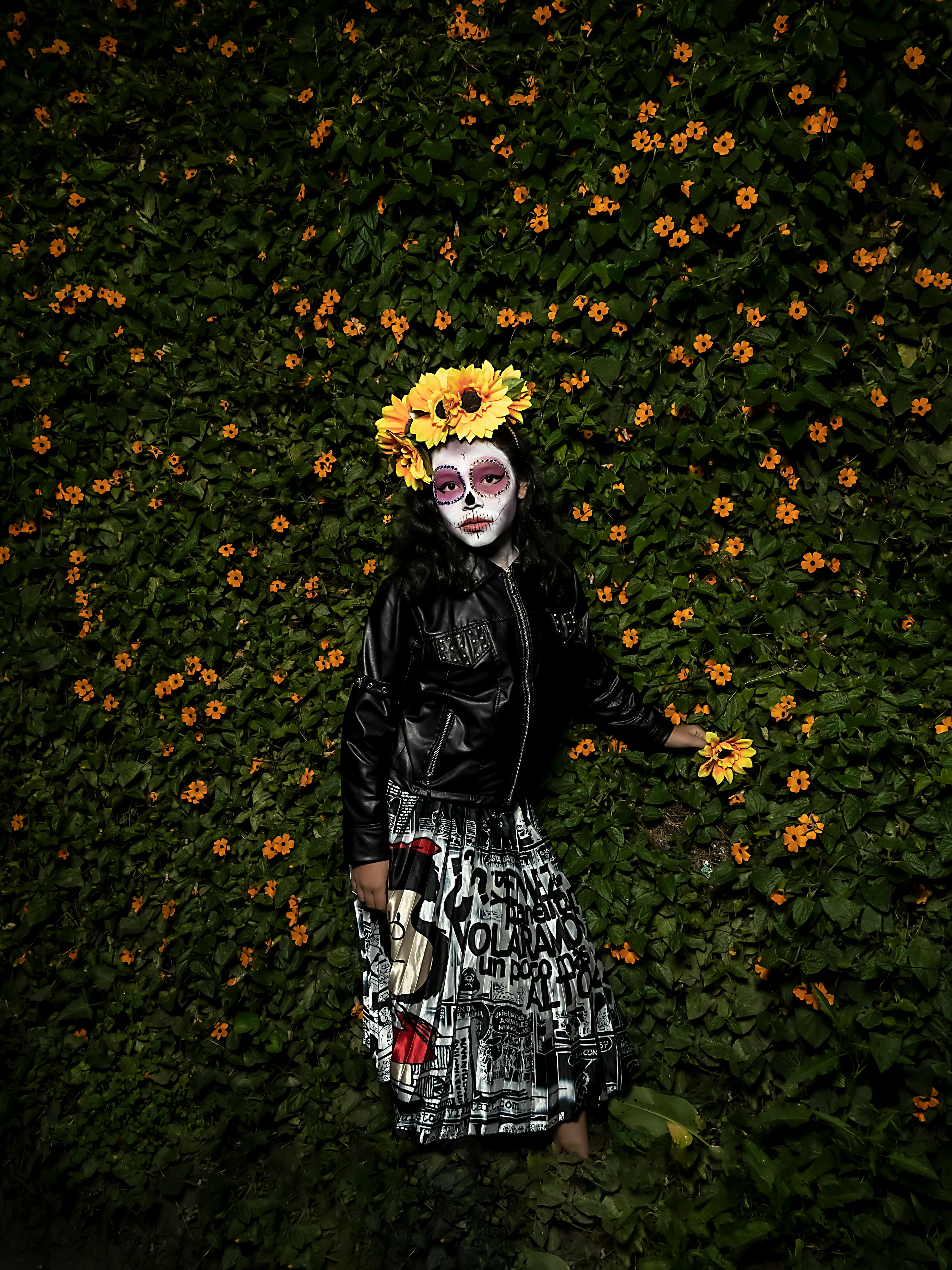Woman with face paint in a field of sunflowers celebrating Day of the Dead.