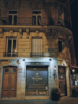 Illuminated café facade on a Paris city street at night showcasing urban charm.