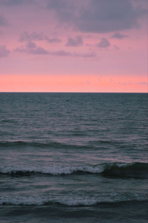 Free Tranquil ocean scene with pink twilight sky, capturing calm waves and a serene horizon. Stock Photo