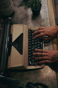 Close-up of hands typing on a vintage typewriter indoors.