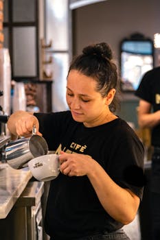 Barista skillfully pours milk into a coffee cup at a stylish café.