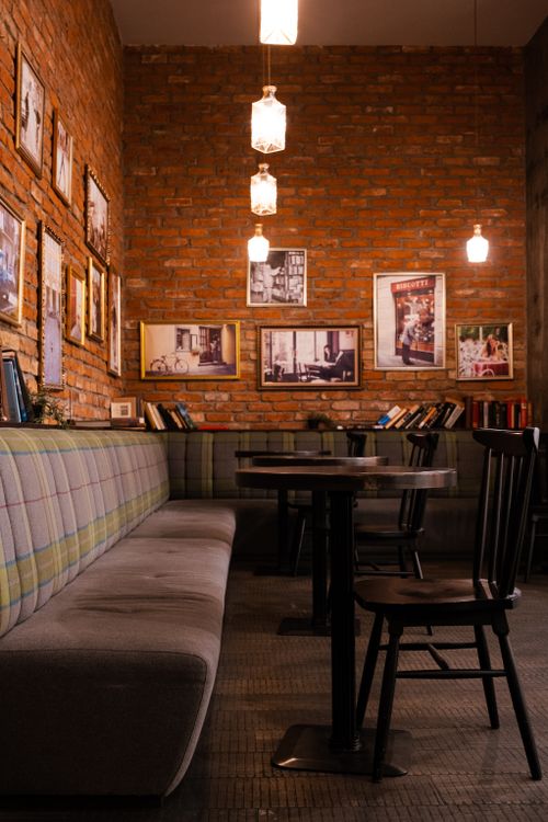 Free Warm and inviting cafe interior featuring brick walls, cozy seating, and ambient lighting. Stock Photo