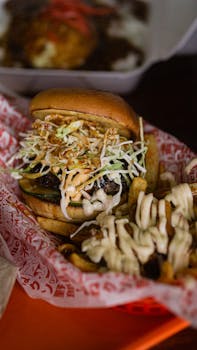 Delicious burger topped with coleslaw and cheese fries on the side.