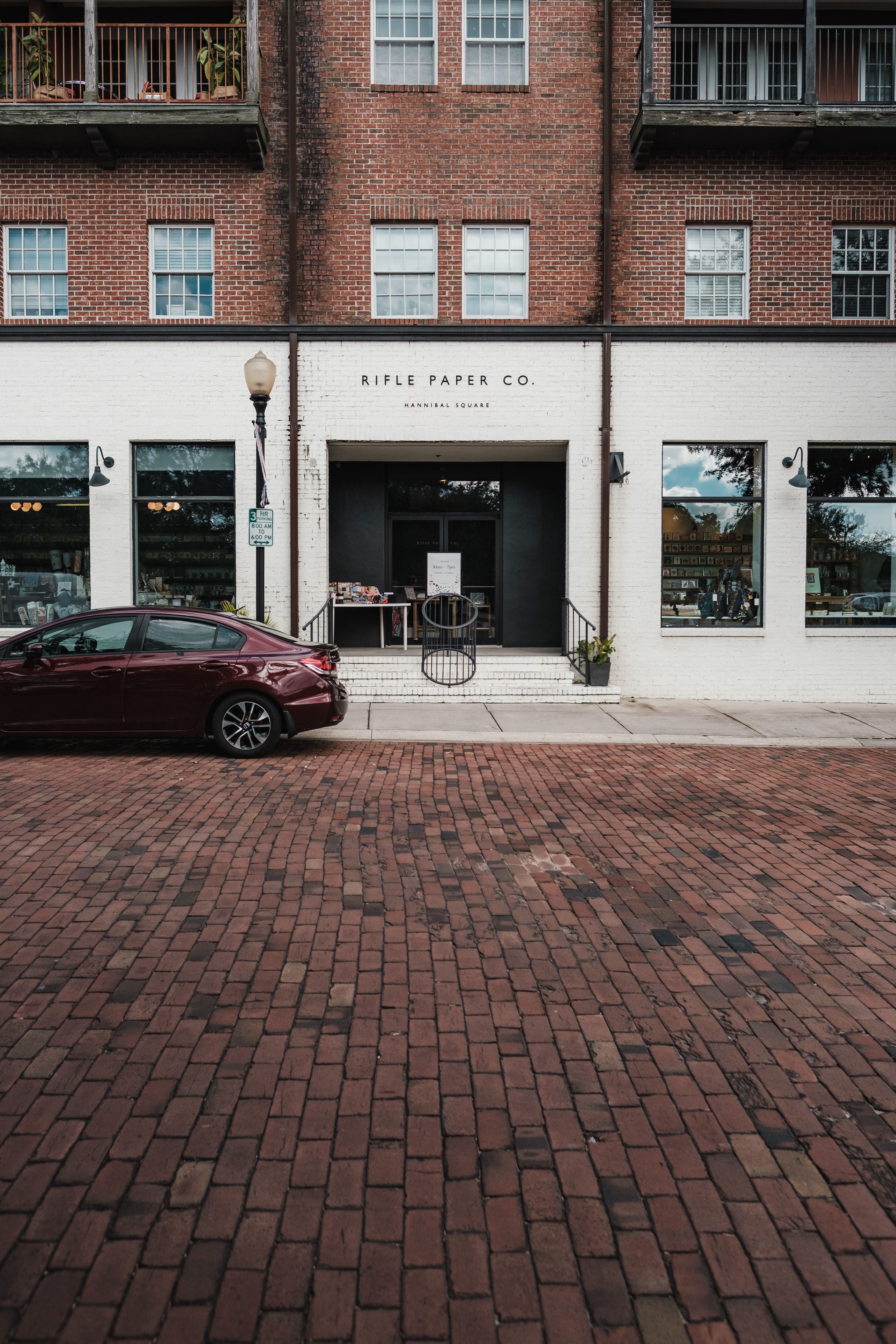 Red Car Parked in Front of White and Brick Building · Free Stock Photo
