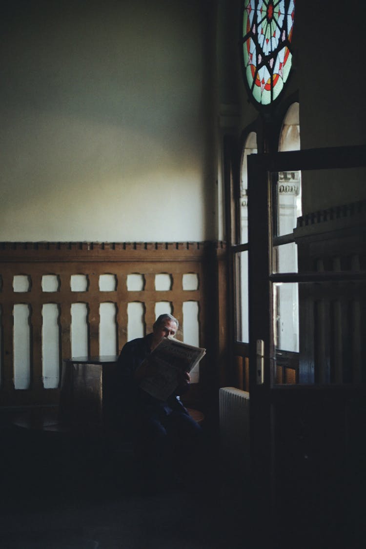 Man Reading Newspaper Near Windows