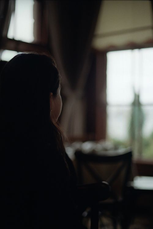 Free Silhouette of a woman contemplating by a bright window in a cozy room. Stock Photo