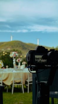 Camera on gimbal filming a beautifully set outdoor banquet table with scenic hills.