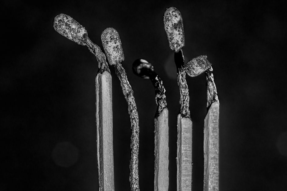 Close-up grayscale shot of burnt matchsticks, showcasing artistic abstraction.