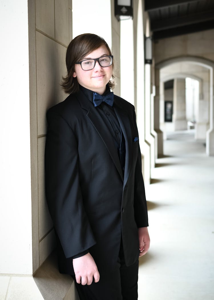 A Teenager In A Suit Leaning On The Wall