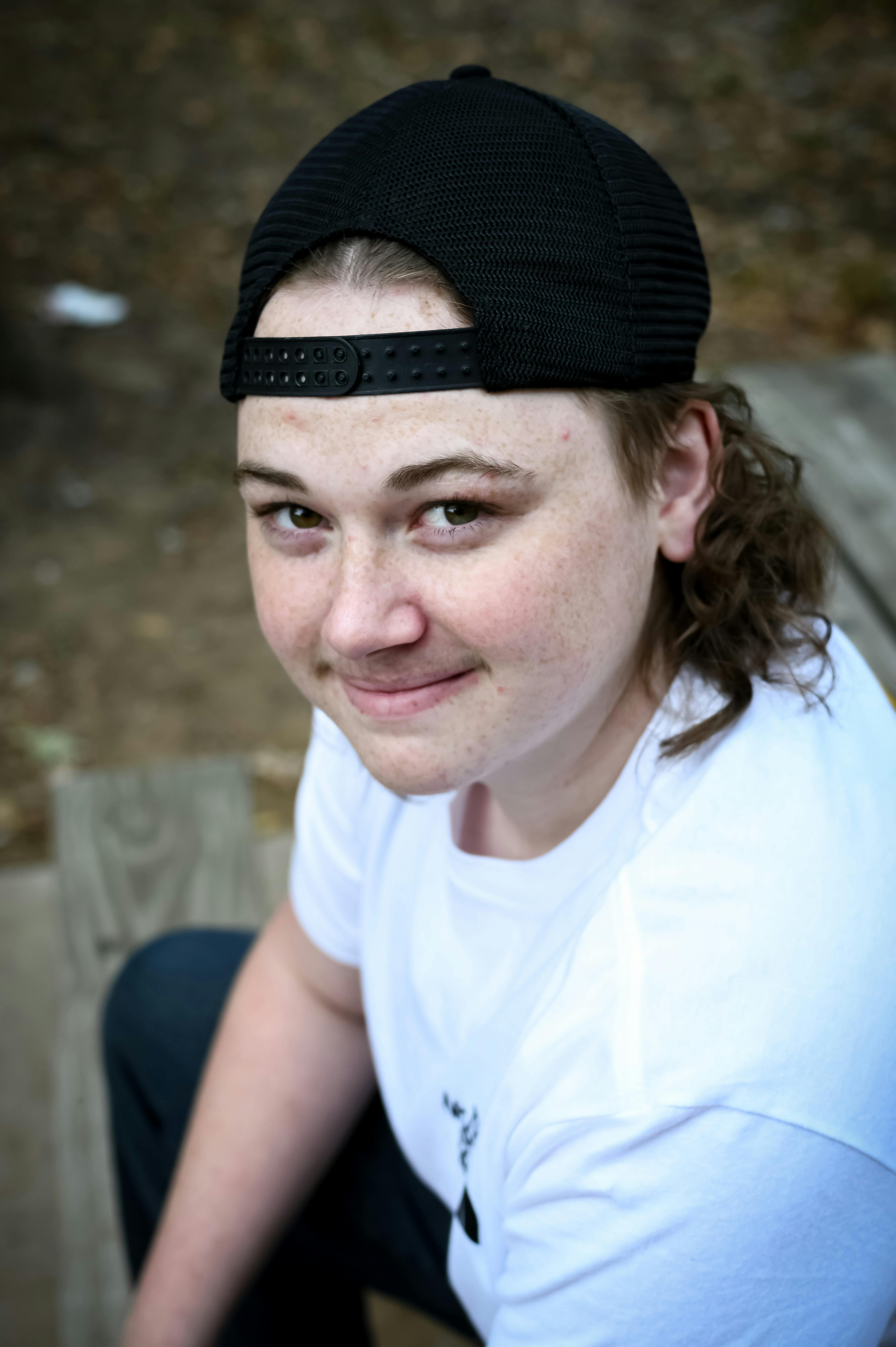 young woman in white crew neck shirt wearing black cap