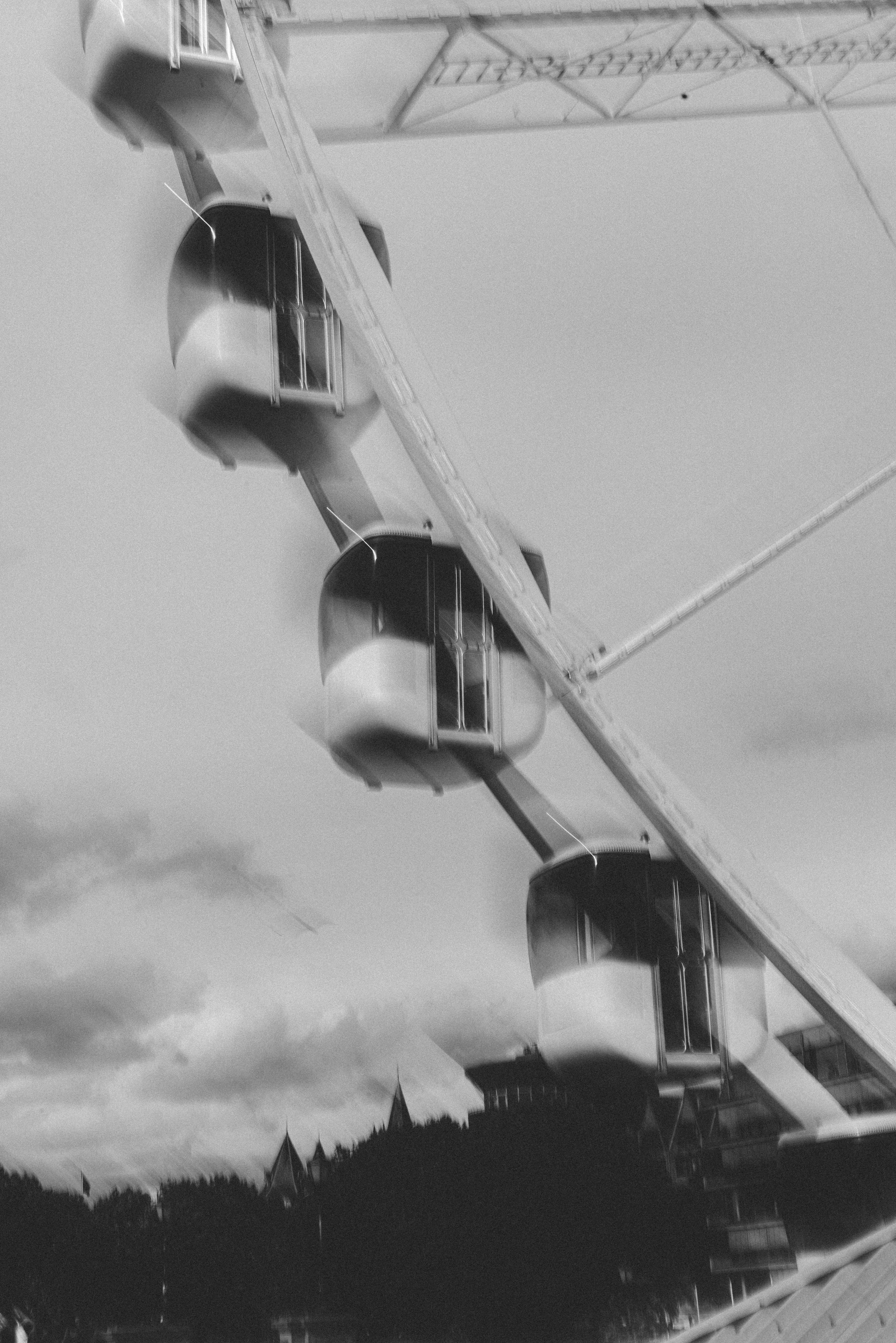 Monochrome close-up of a Ferris wheel with clouds in the background for a timeless feel.