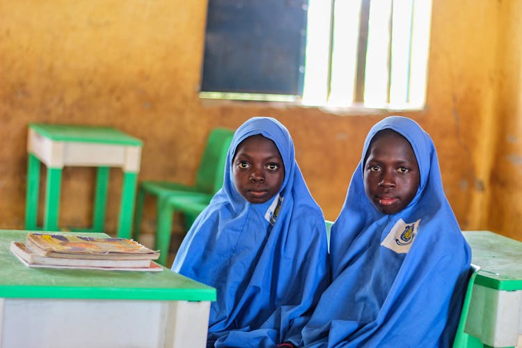 Two Children Wearing Blue Hijabs Inside A Classroom