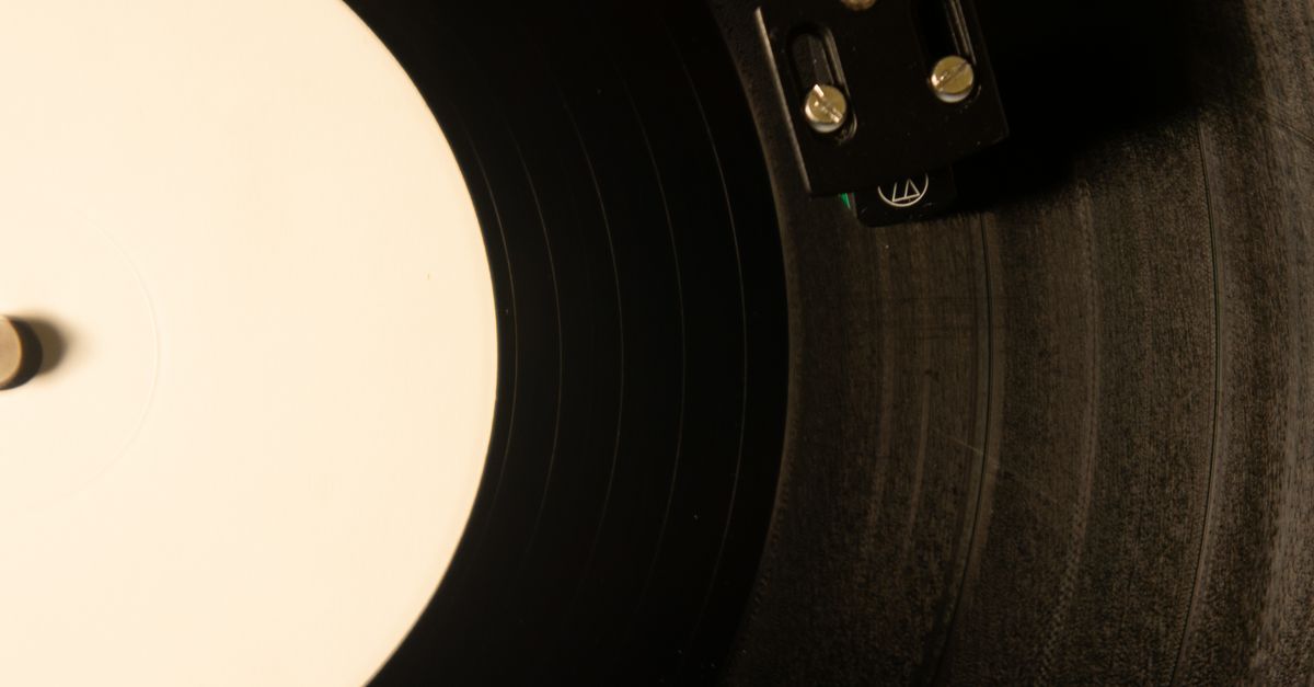Close-up of a vinyl record needle touching grooves, warm lighting, vintage aesthetic