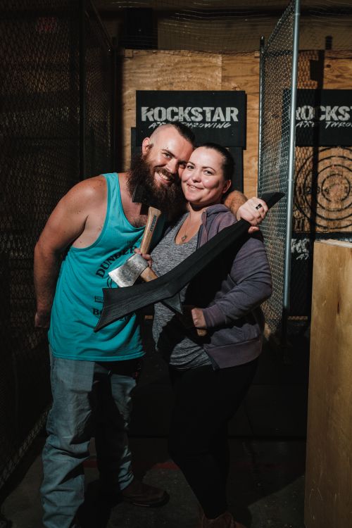Free A cheerful couple posing with axes at an indoor axe throwing venue. Stock Photo